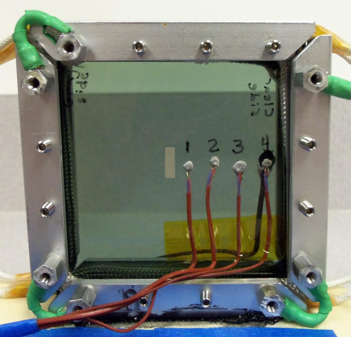 Heating cell with thermocouples measuring the gradient. The yellow rectangle marks the area of the sample that is illuminated by the light beam.
